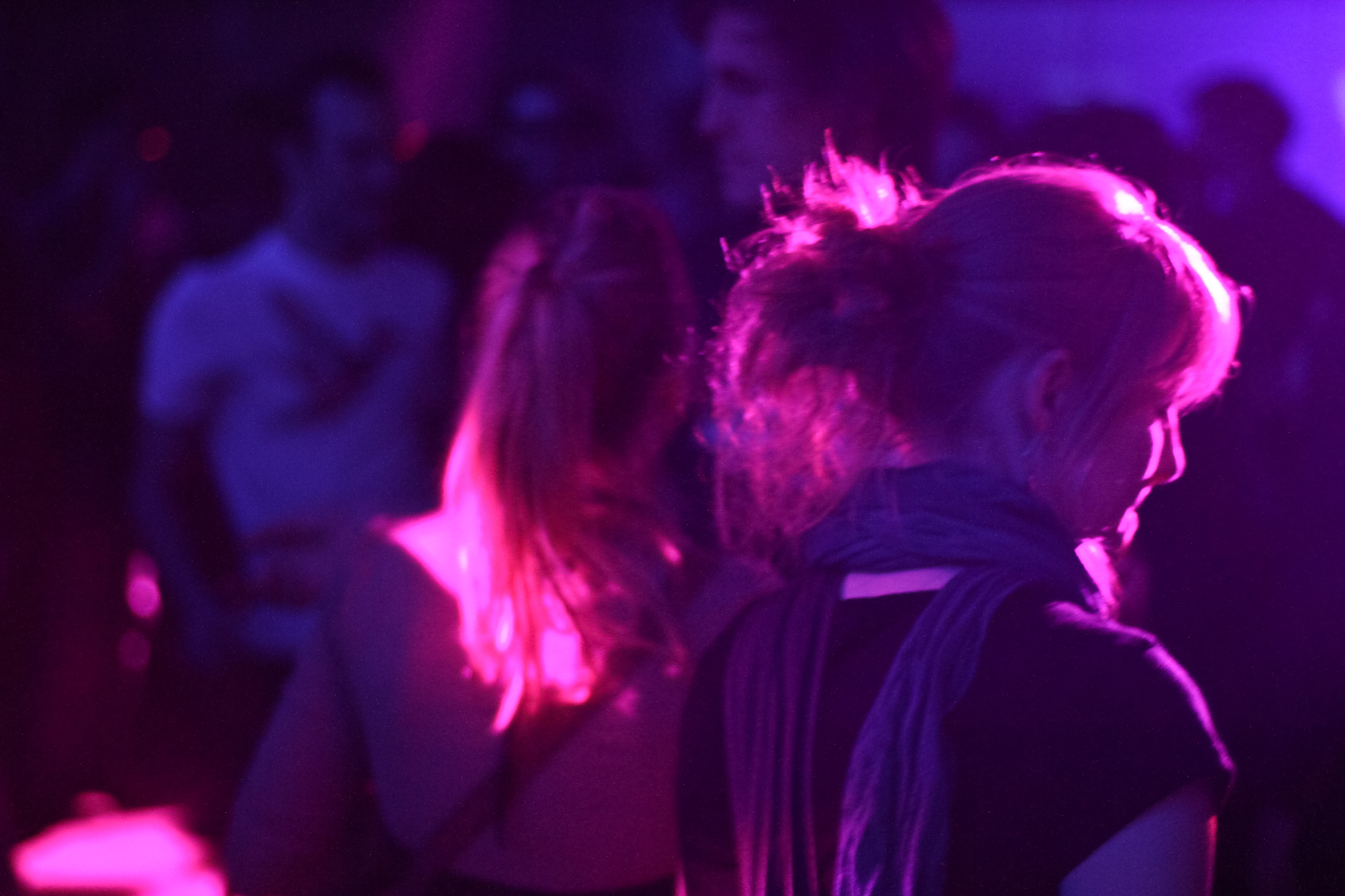 people on a crowded, purple - lit night at the club