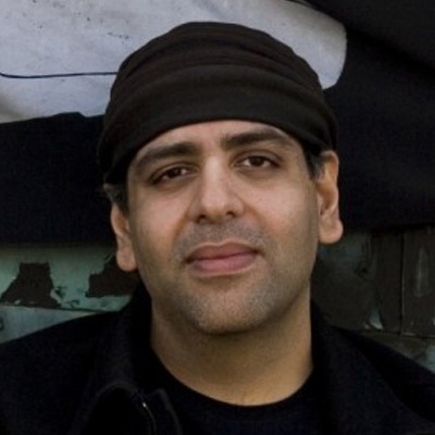 man with black clothes and headwear in front of wall