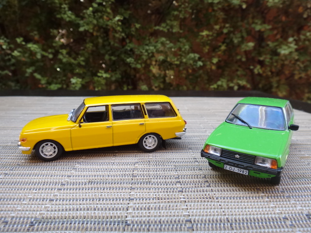 one green car parked near a small yellow car