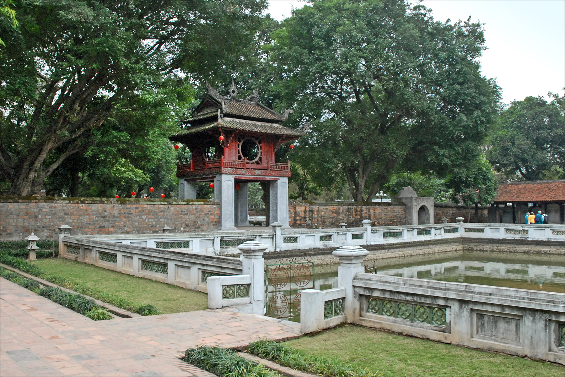 the pagoda with its red roof is near a small pond