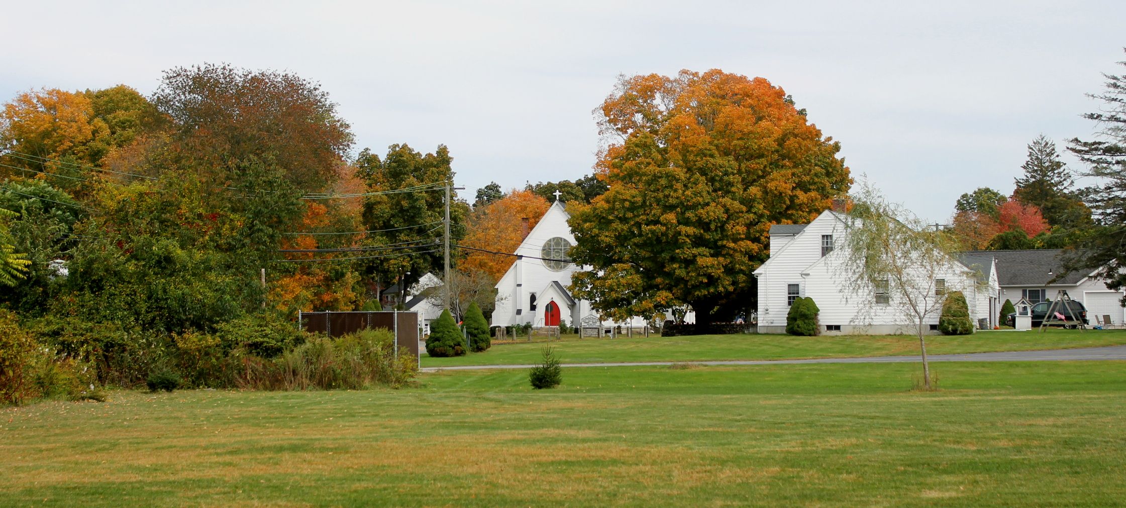 white house in fall trees with a paved road