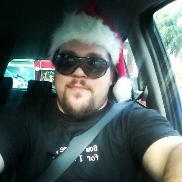 a man driving his car wearing a santa hat