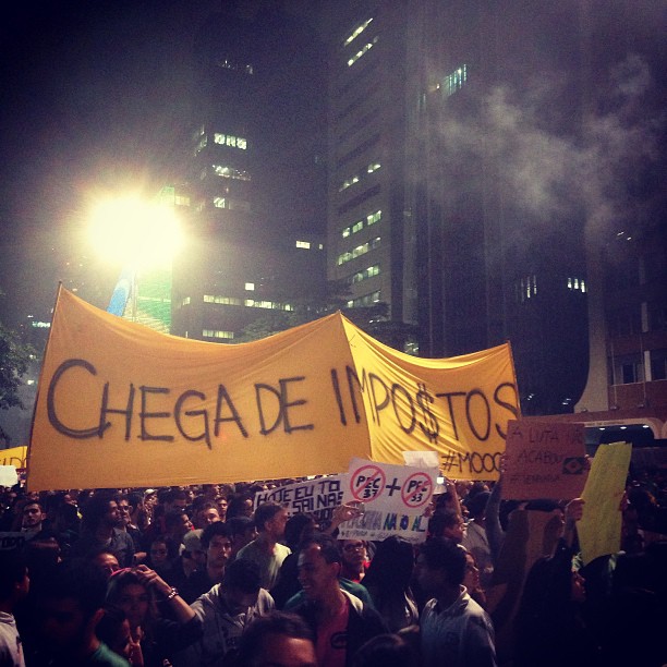a protest with protesters holding up a large banner that reads, chega dei impostos