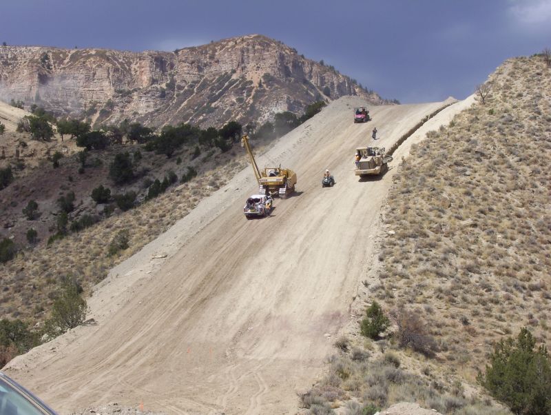 several trucks driving down a road on top of a mountain