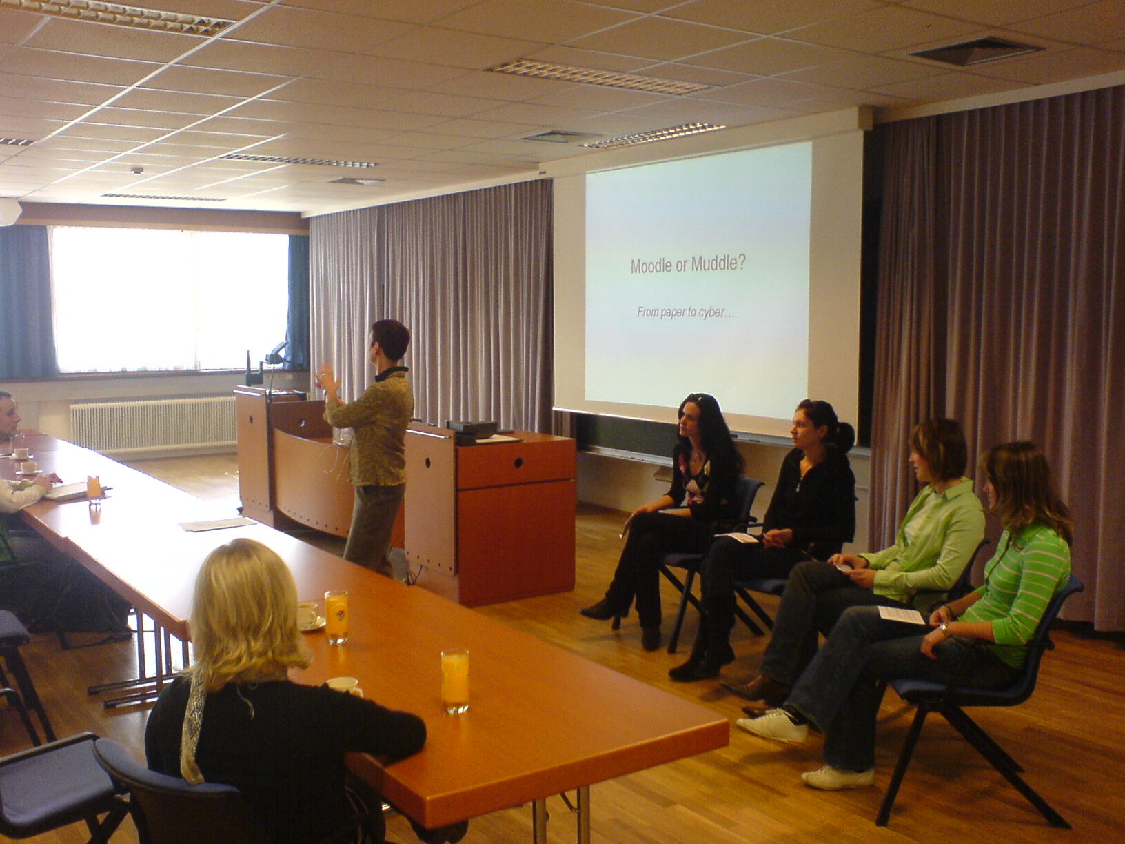 a group of women sitting at a table with one person standing