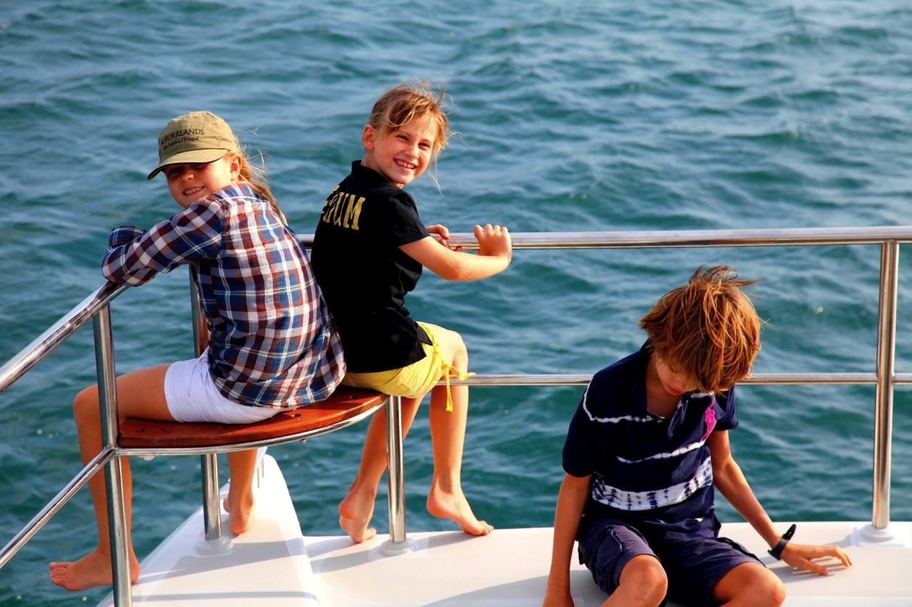 two boys and one girl are sitting on a boat