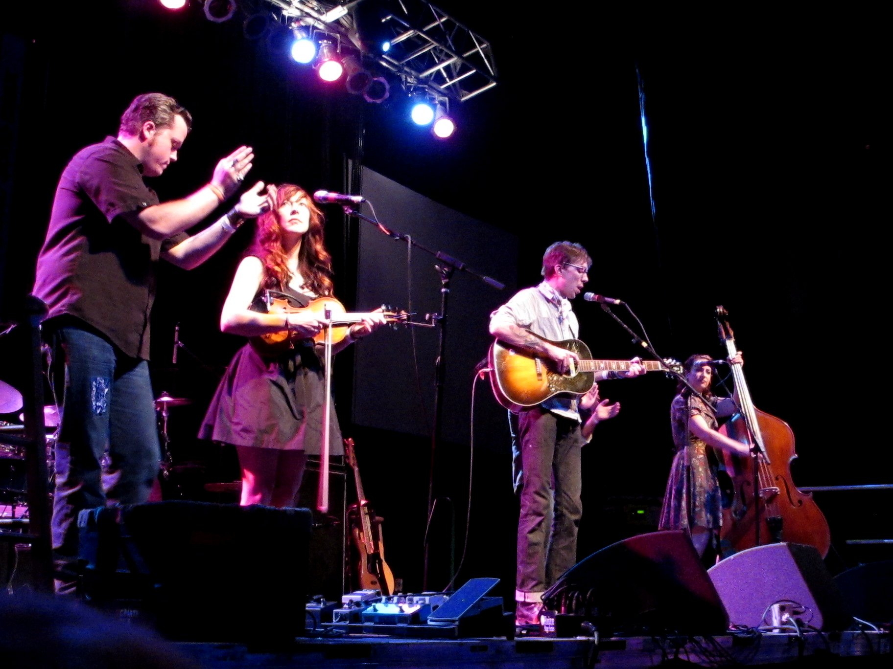 a man singing at a stage while playing guitar