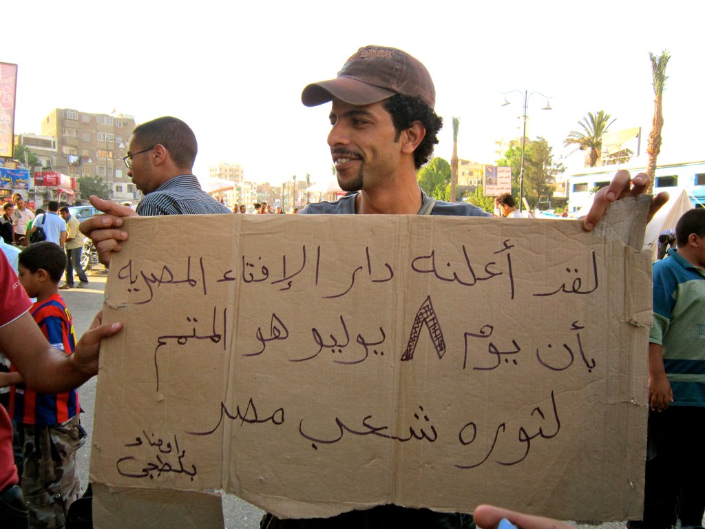 an arabic protest with signs and men with hats