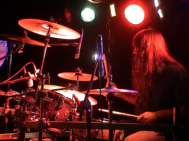 a man playing drums on stage with a set of lights