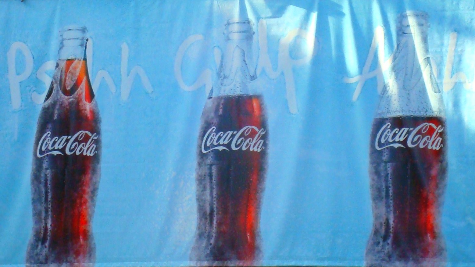 three coca cola bottles on display outside