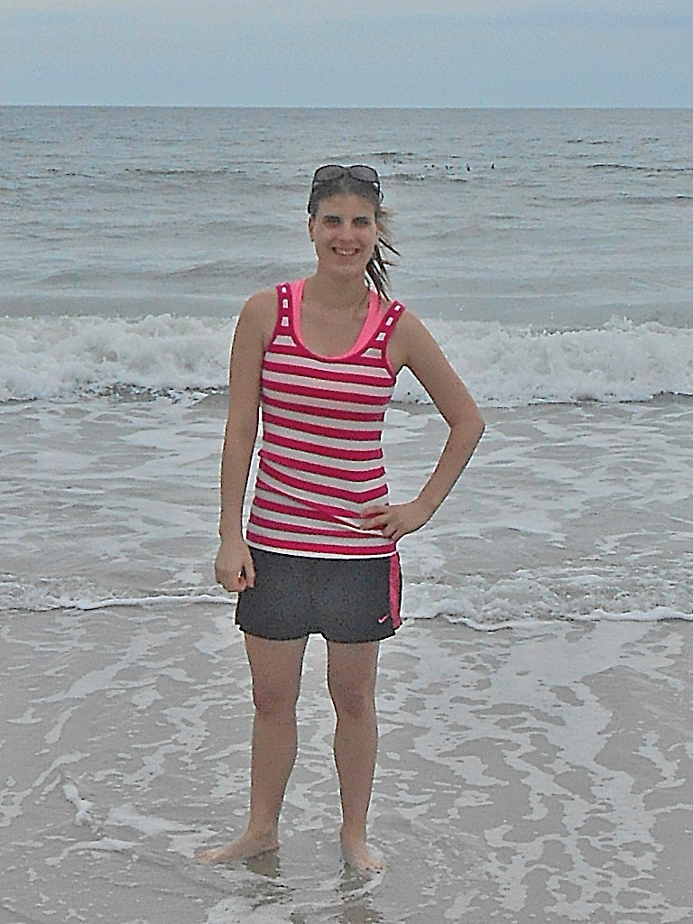 girl with pink and white striped shirt posing in front of the ocean