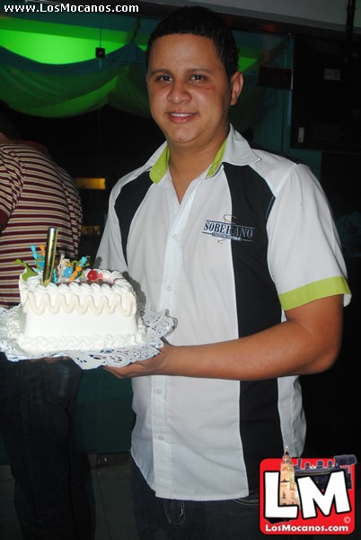 a man holding a cake with candles on it and the man is in the background