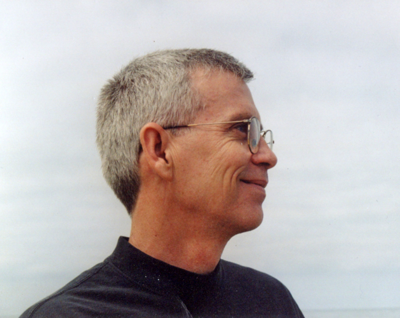 a man with short gray hair and glasses smiles