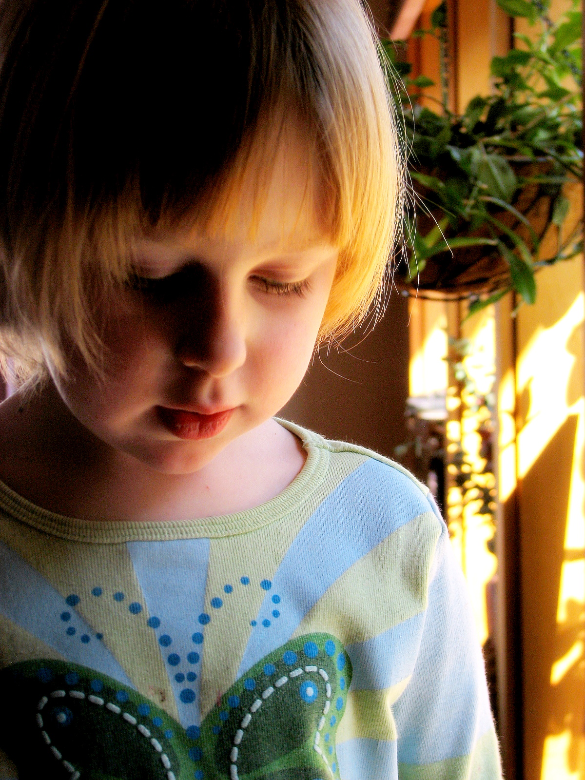 a child in a blue and green shirt looking down