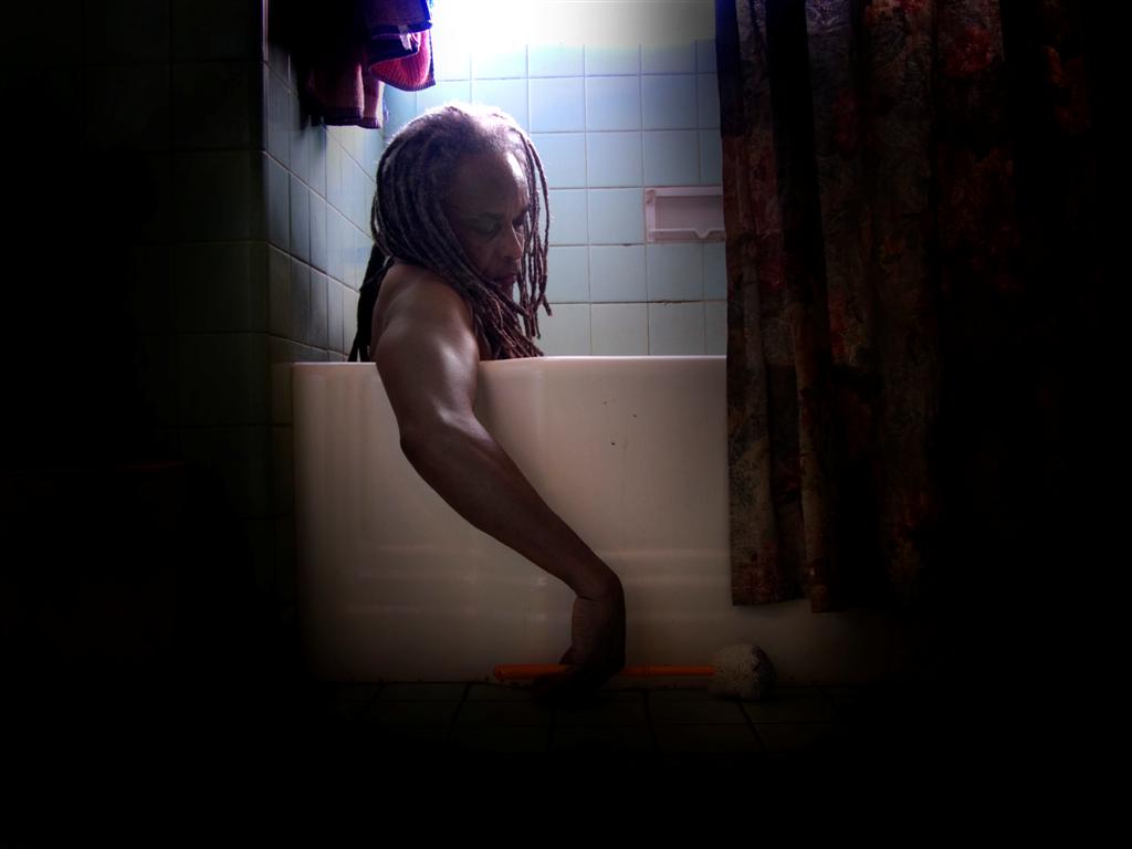 a man is leaning against a bathtub in a dark room