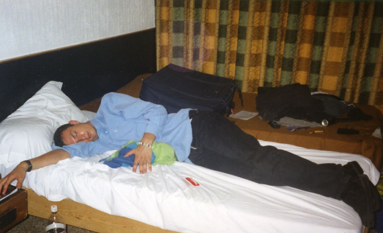 a man is sleeping on a bed with a suitcase