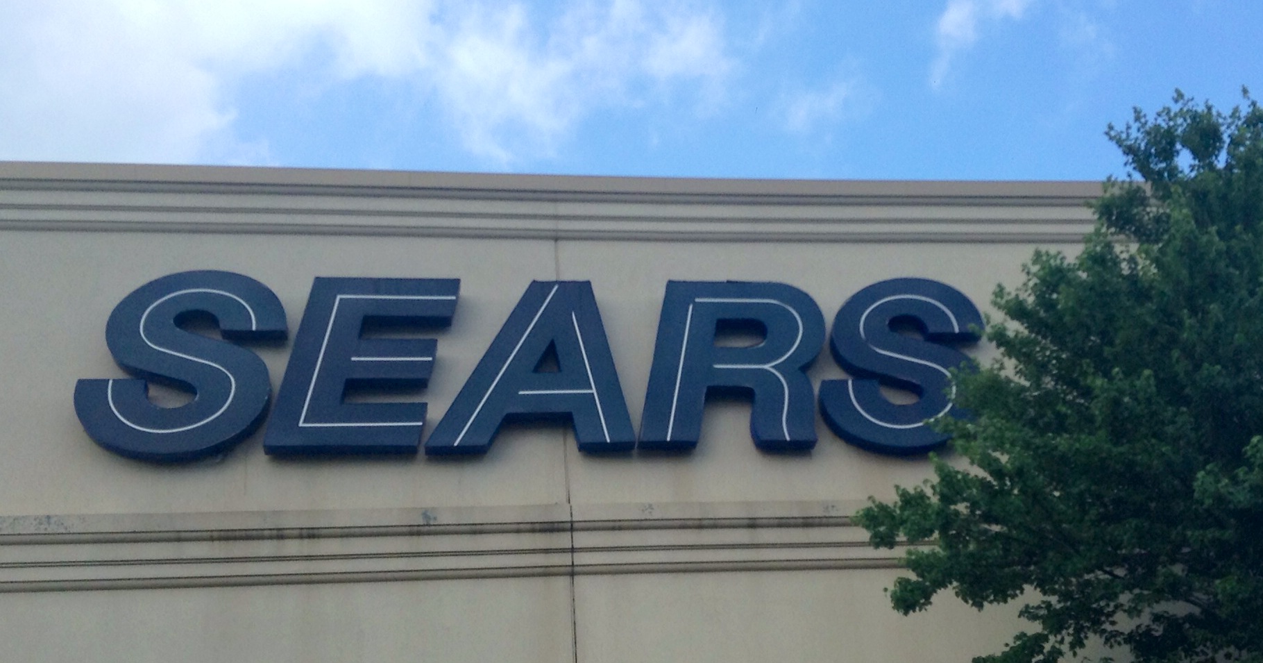 the exterior of an outdoor clothing store featuring an arched sign that reads searss