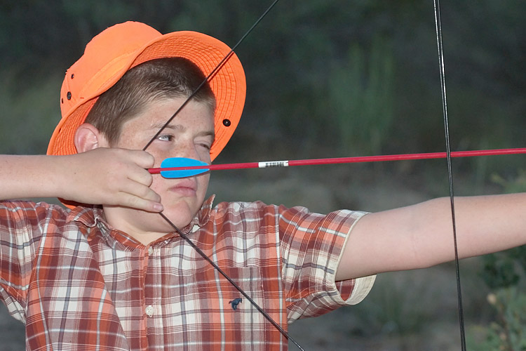 the boy is practicing archery, and aiming arrows at his target