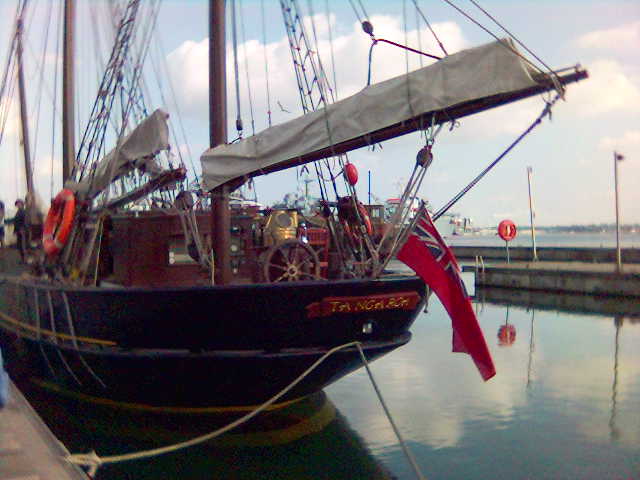 a sailboat parked in the water and people near