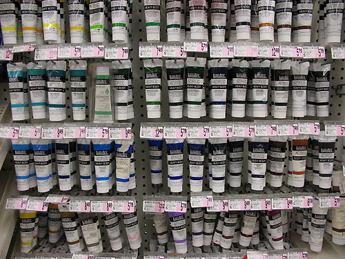 many jars of different colors of paint are stacked on each other