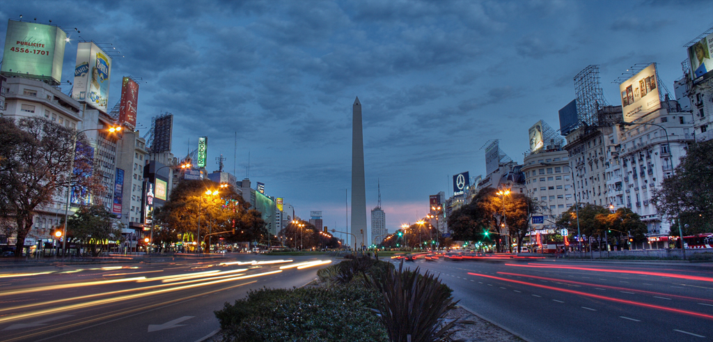 a street is lit up as dusk approaches the obelisk