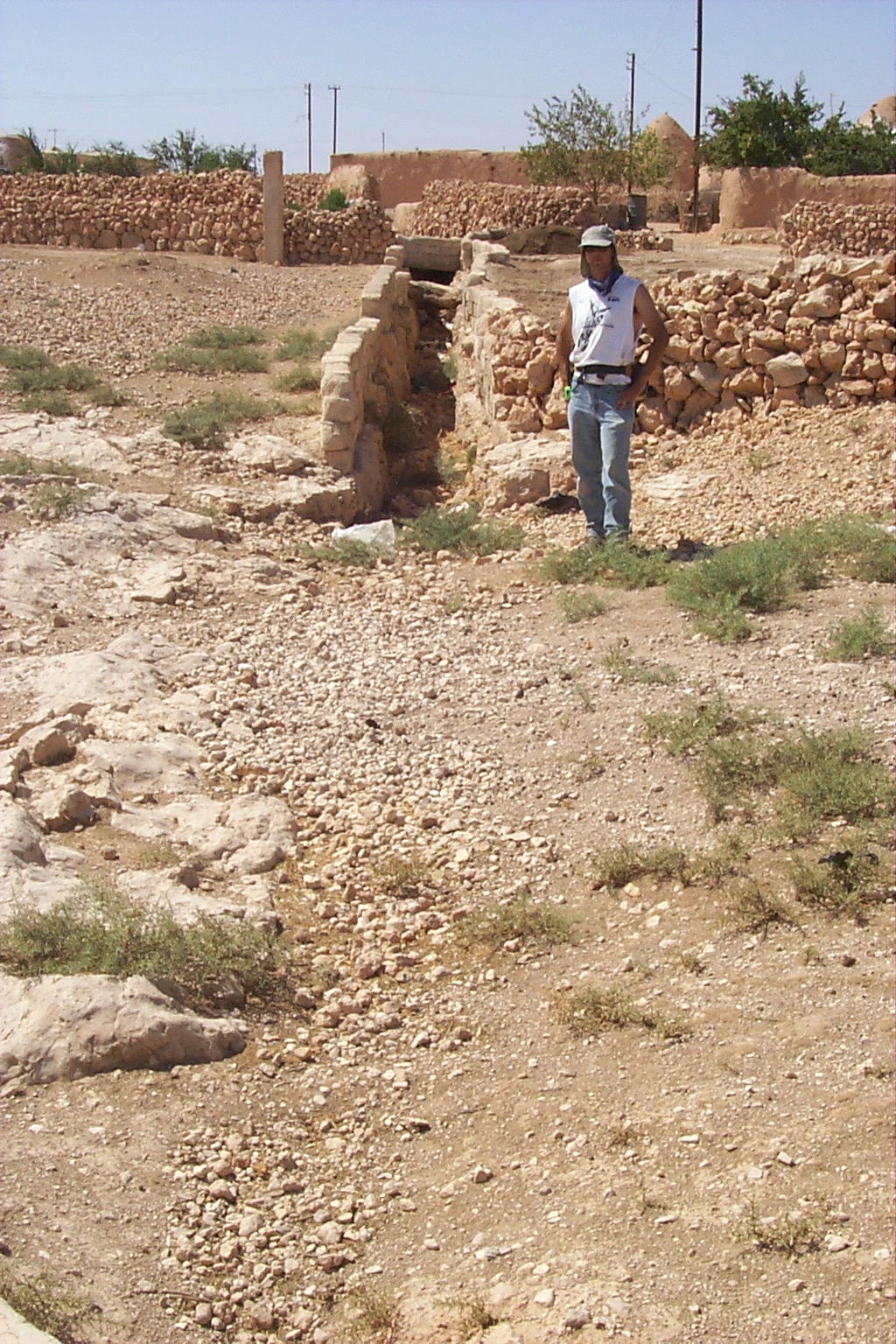a person in a hat looking at rocks and sand