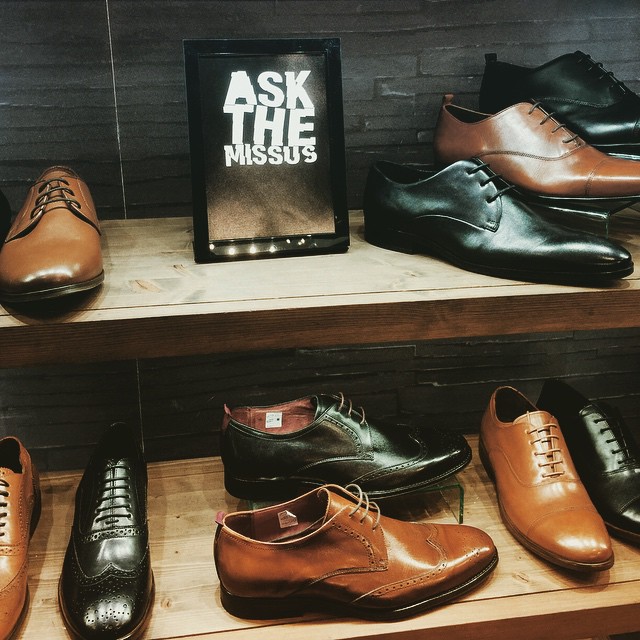 a display of men's shoes on wooden shelves