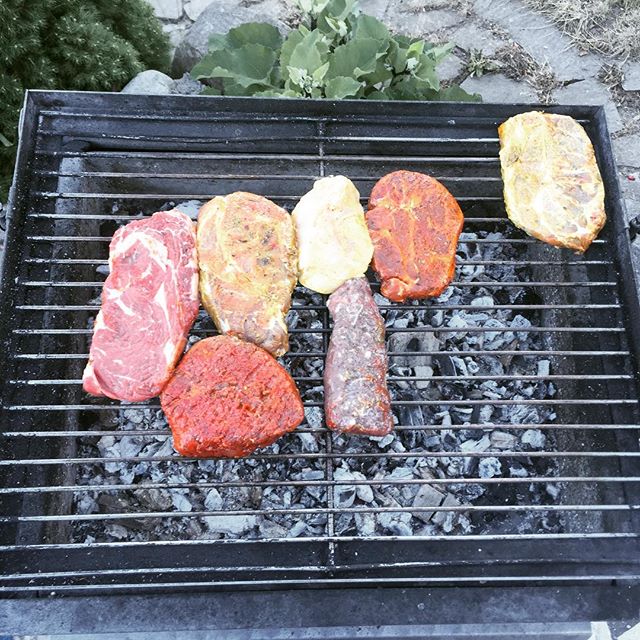 some meats and hamburger patties on a grill