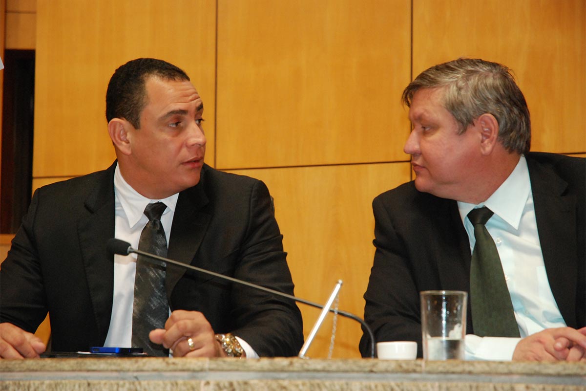 two men sitting at a table with a microphone