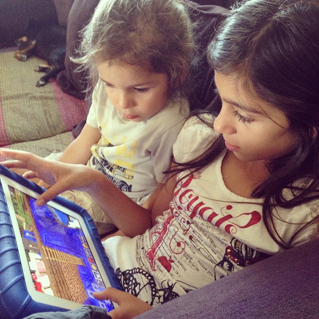 two s are playing on a tablet