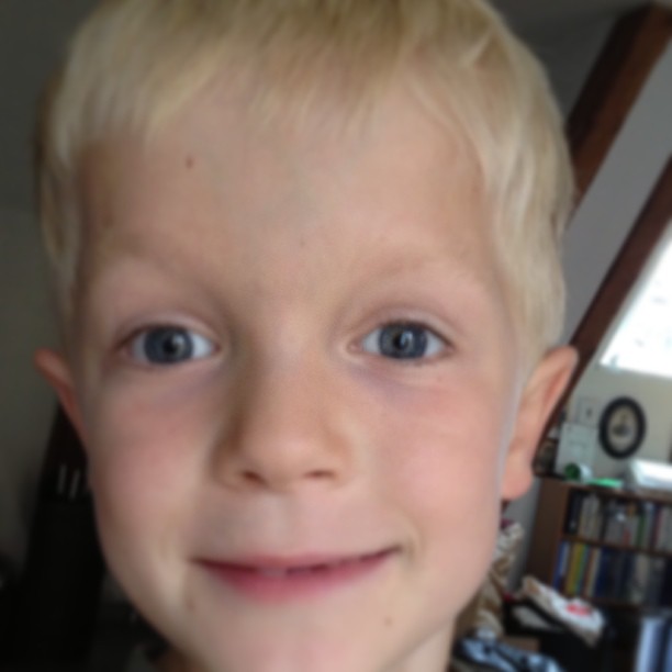 a little boy with blonde hair looking into the camera