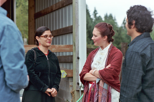 people stand in a row with one woman wearing glasses and the other standing with her arms folded