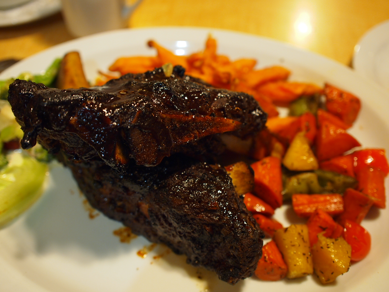 grilled meat, vegetables and a salad are on the white plate