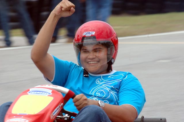 a child in blue and red helmet riding a small race car