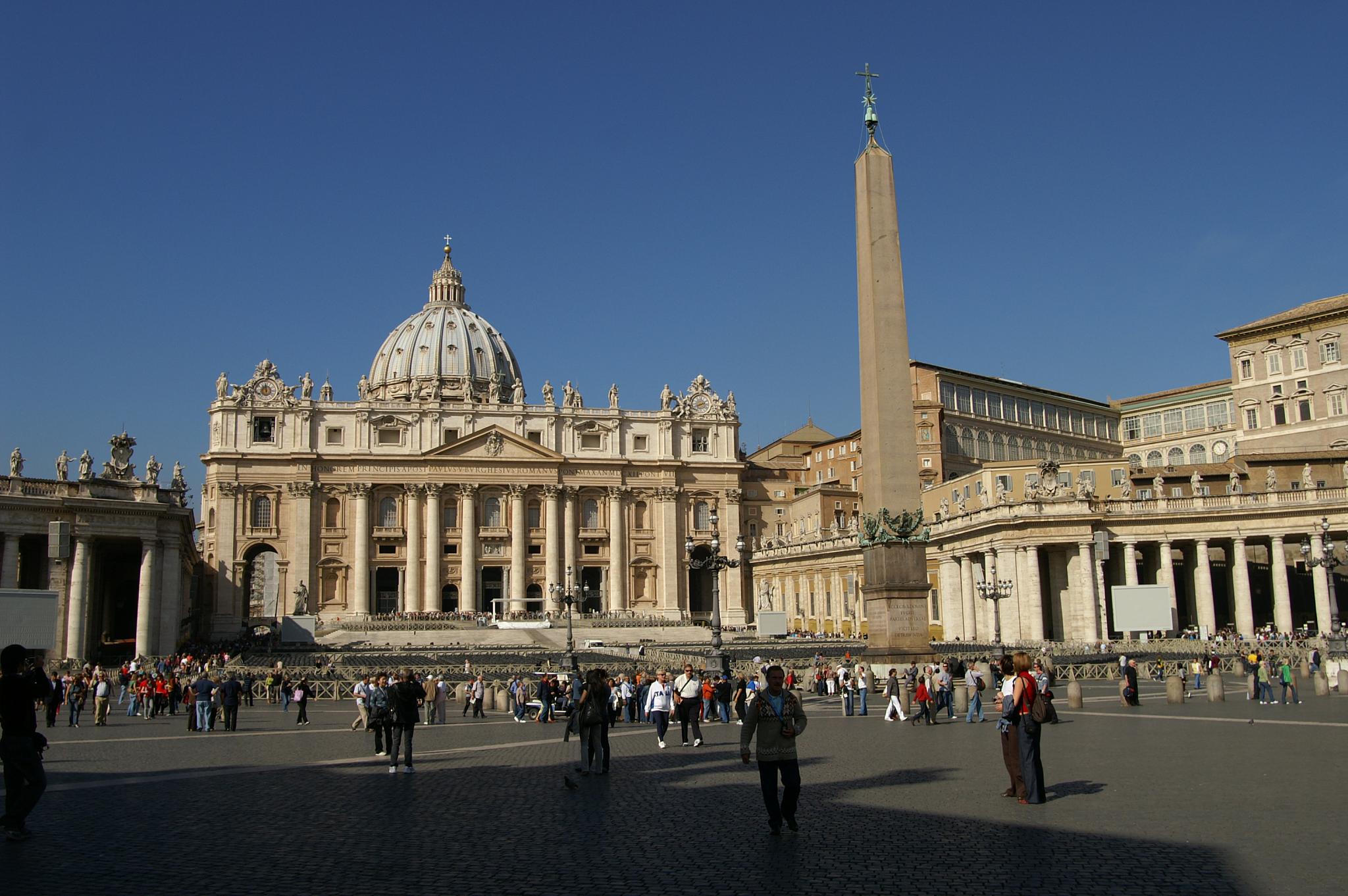 people in a square outside a cathedral and tall column