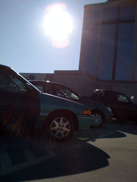 the three cars are parked in the lot in the sunshine