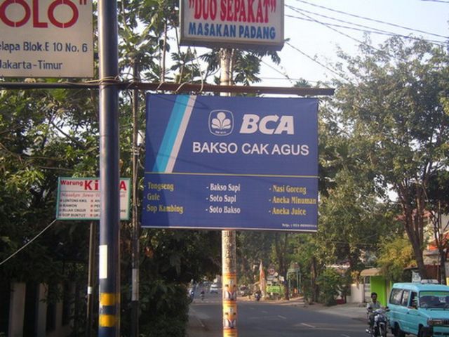 a street sign with a blue car parked in the road