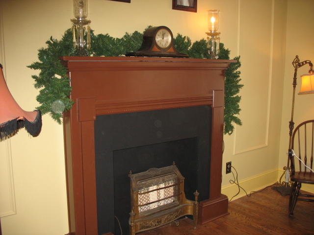 a room with a fireplace, wooden floor and a christmas tree on the mantle
