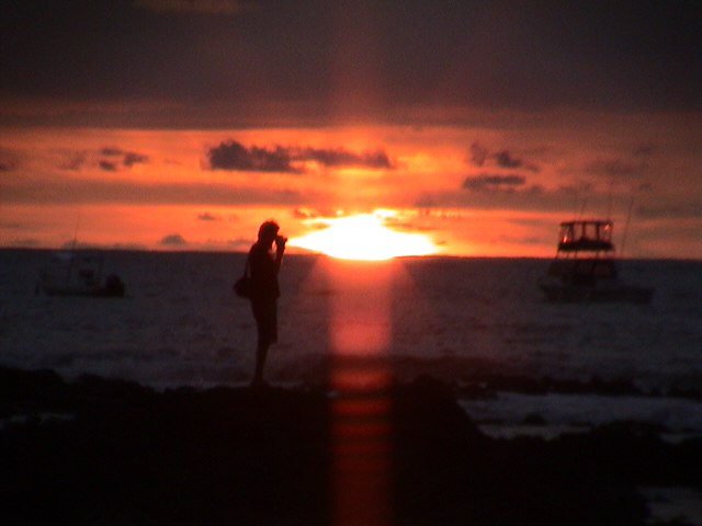 a woman standing at sunset next to the water
