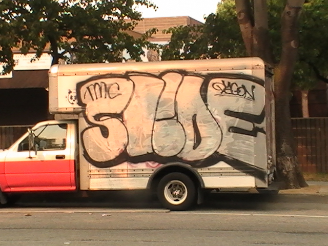 a truck covered in graffiti on the side of the road