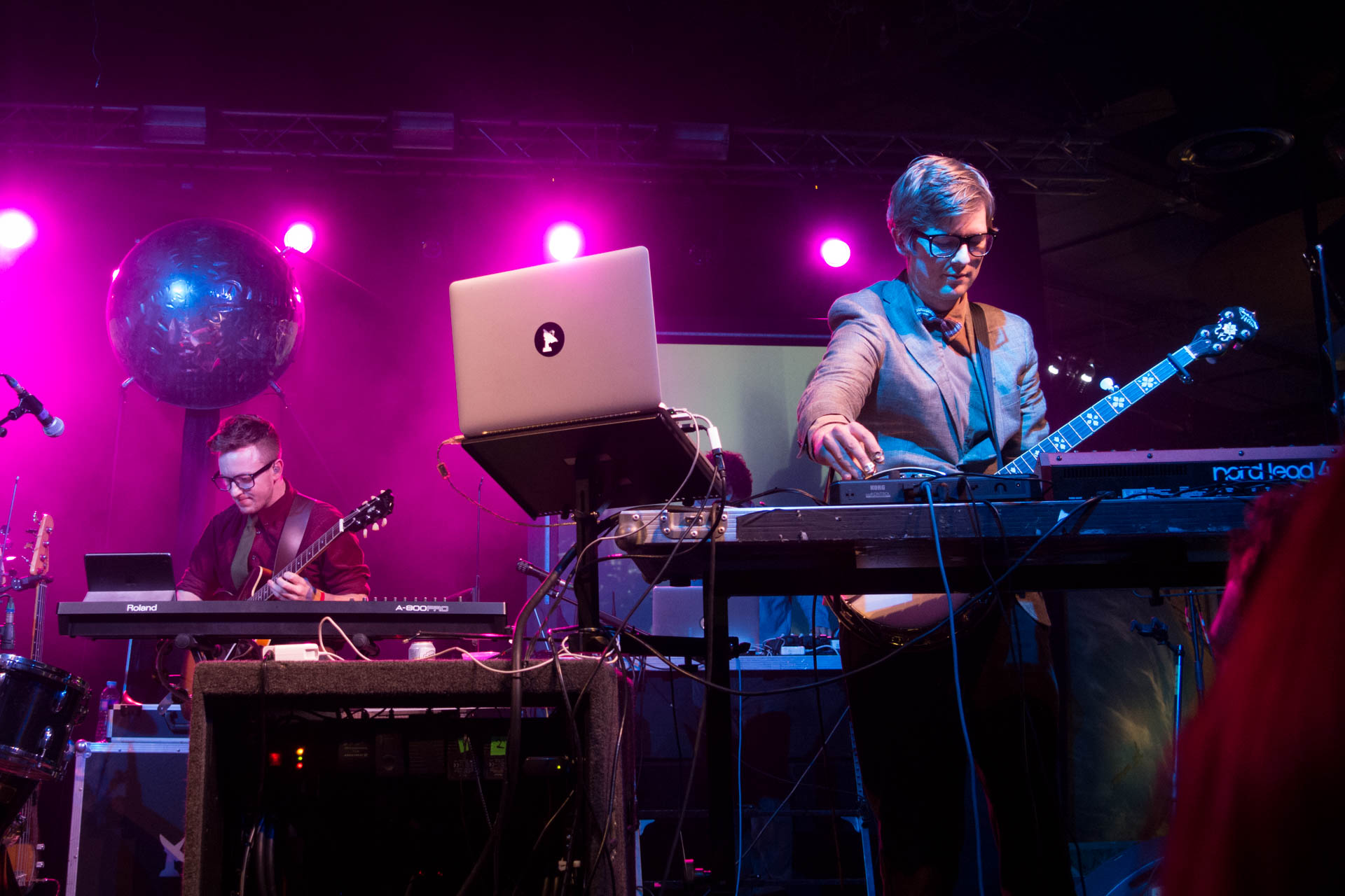 a man and woman playing on keyboard in front of stage lights