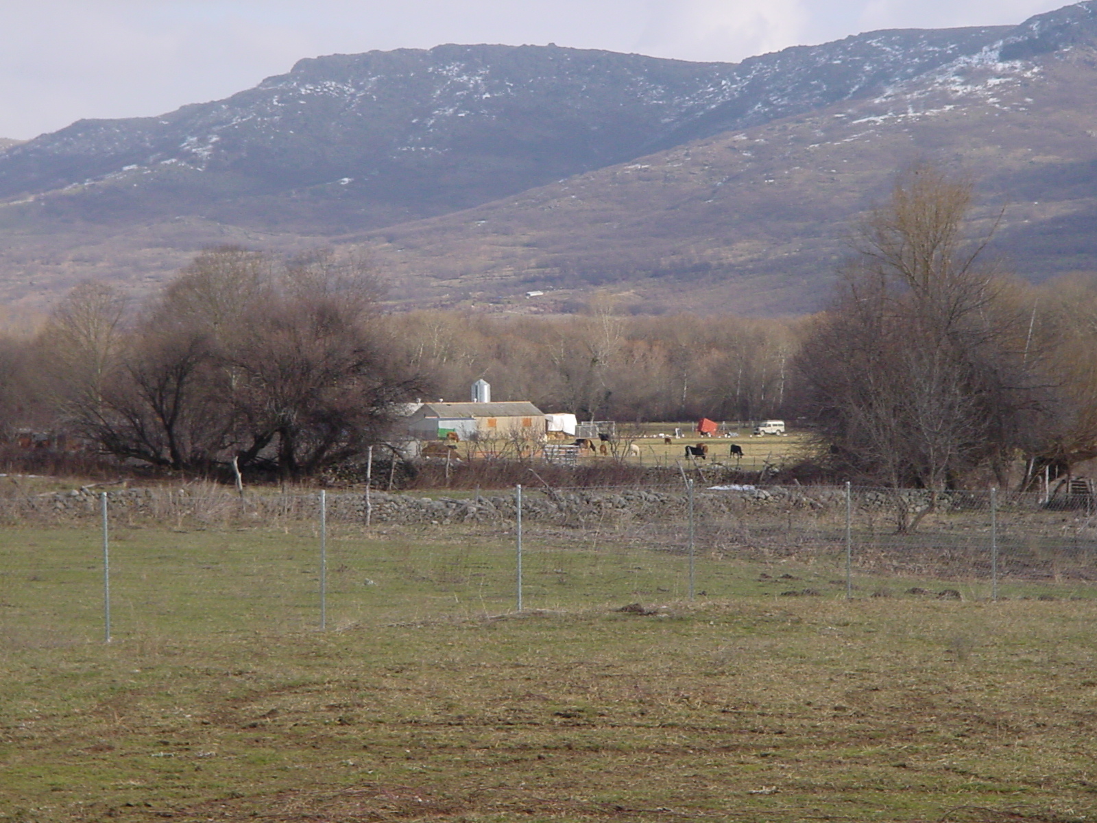 the mountains are behind the farm with a large building