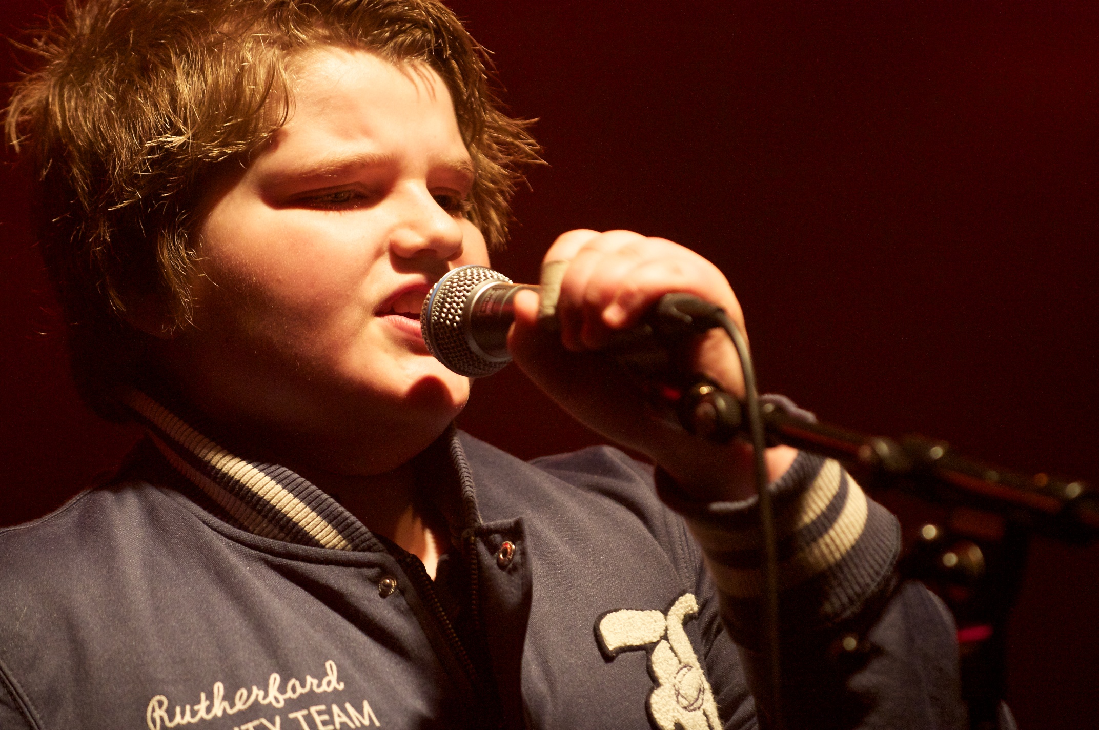 a young man holding a microphone while singing into a microphone