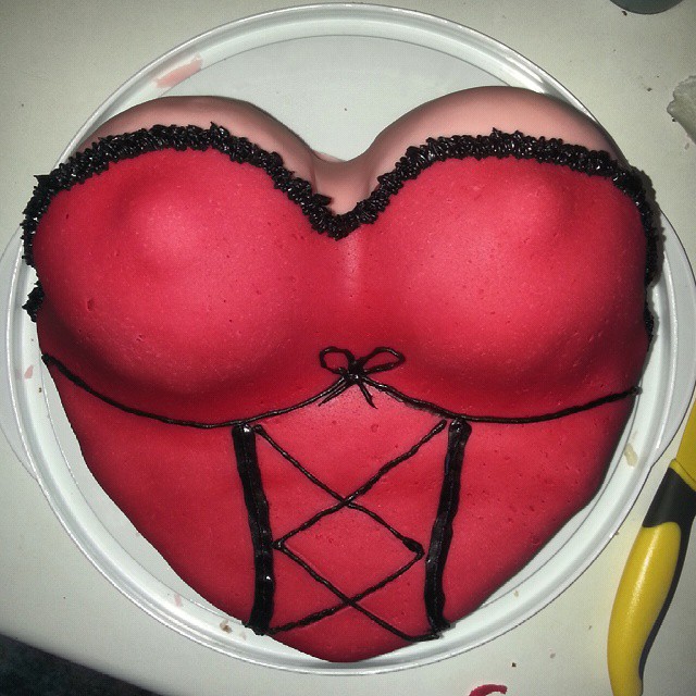 red cake decorated like a woman's torso, sitting on a plate