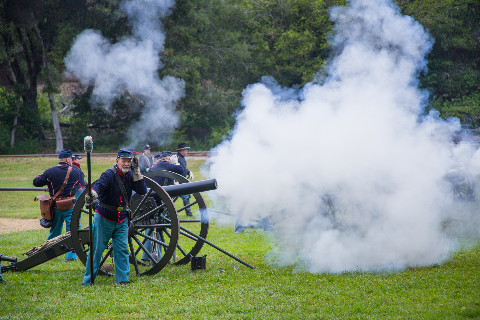 men in uniforms stand near two cannon