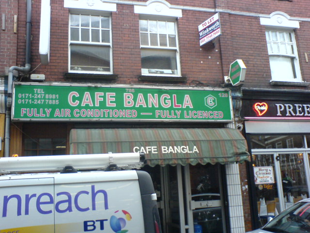 a coffee shop with several signs and cars parked outside it