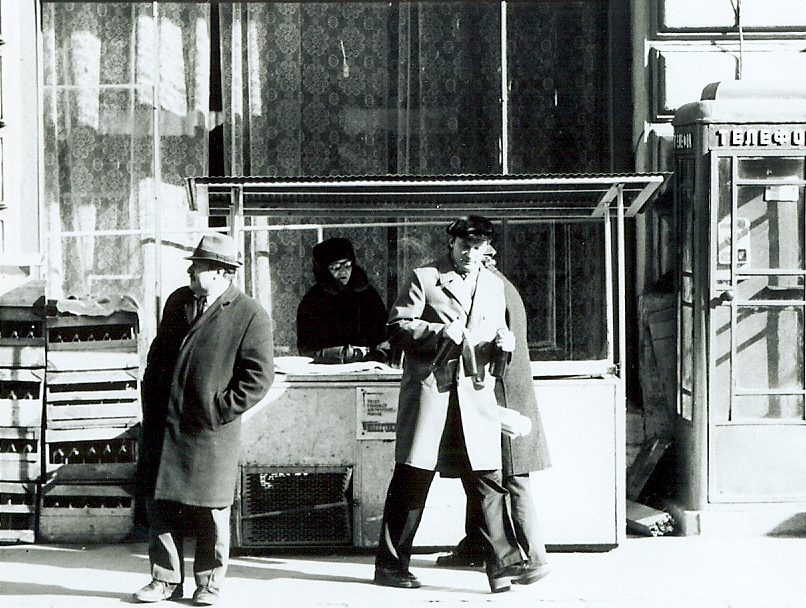 some men are standing outside a bank in the rain