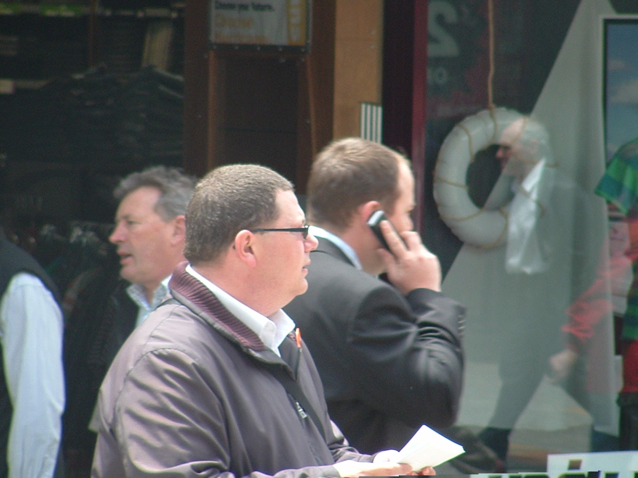 a man talking on a cell phone next to other people