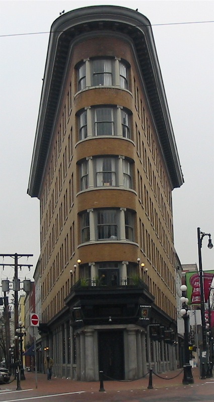 a very tall building sits at the corner of the road