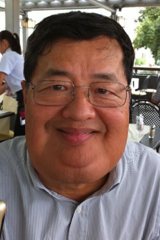 an asian man wearing glasses smiling for the camera
